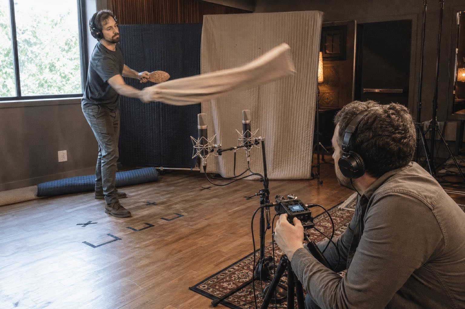 Two Foley artists record moving canvas in front of a stereo microphone pair